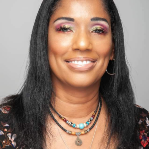 A smiling woman over 40 with vibrant pink and gold eyeshadow, showcasing a professional makeup look by Beauty with AS in Houston.