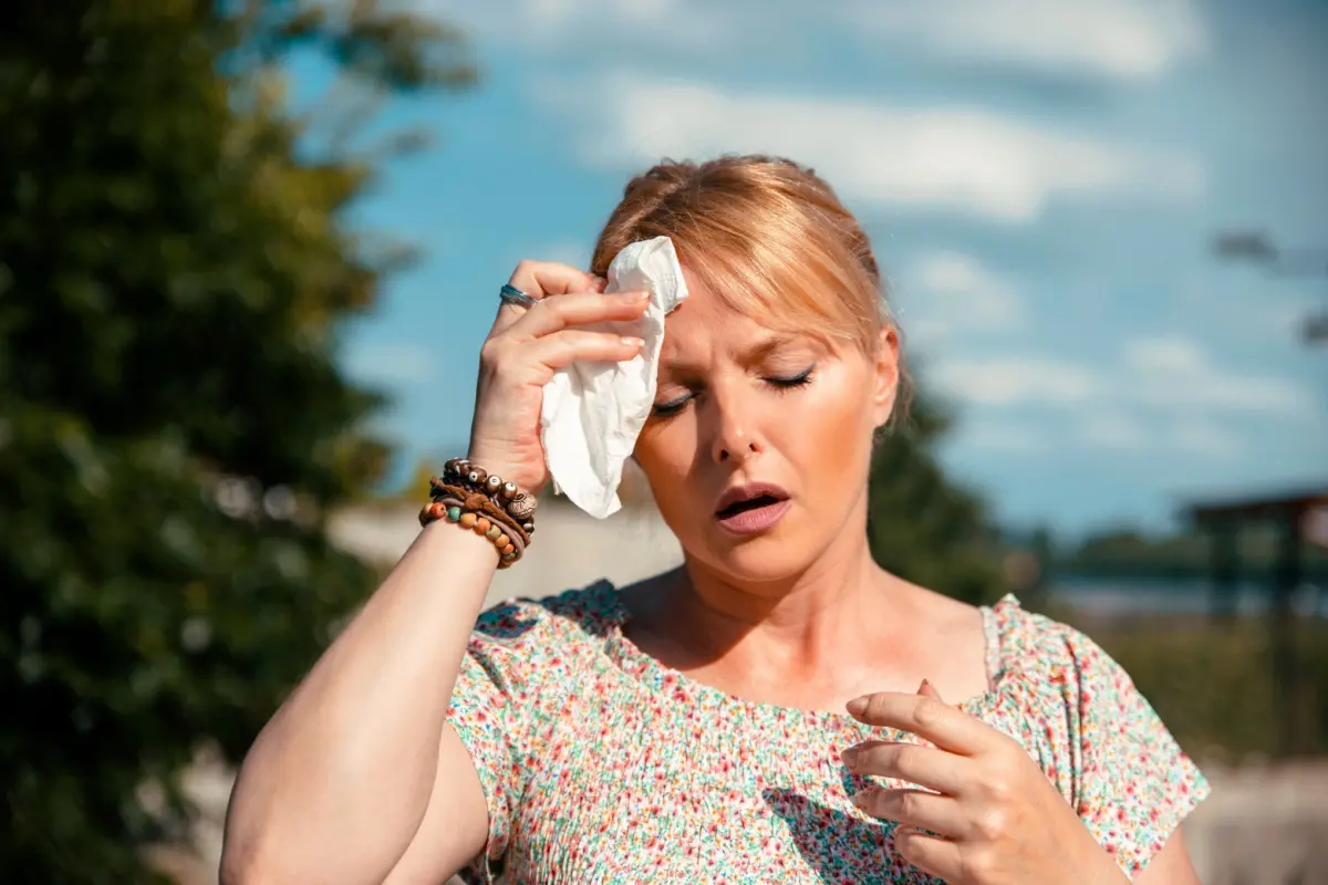 bwaBlog 14 Sweatproof makeup tips 2025 for mature skin – woman wiping sweat off forehead in summer heat