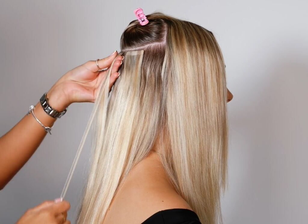 Tape-in hair extensions installed on fine hair, showing how the lightweight adhesive wefts lie flat against the scalp for a natural look.