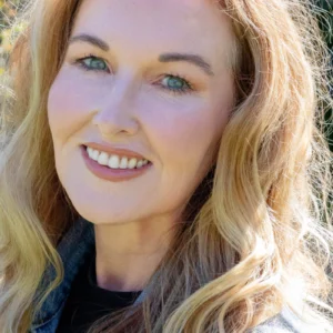 A smiling woman over 50 with radiant satin skin, natural pro-aging makeup, and blonde wavy hair, showcasing a healthy glow.
